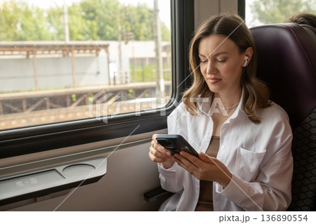Young Woman Uses Smartphone While Traveling on a Train During a Bright Afternoon Young Woman Uses Smartphone While Traveling on a Train During a Bright Afternoon 136890554