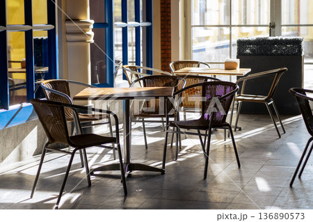 Cozy Cafe Interior With Wooden Tables and Wicker Chairs in Bright Natural Light During the Afternoon Cozy Cafe Interior With Wooden Tables and Wicker Chairs in Bright Natural Light During the Afternoon 136890573