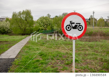 Motorcycle Prohibited Sign Near a Walking Path by a River in a Green Area on a Cloudy Day Motorcycle Prohibited Sign Near a Walking Path by a River in a Green Area on a Cloudy Day 136890584