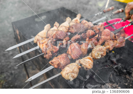 Grilling Skewered Meat Over Charcoal in an Outdoor Setting During a Sunny Day 136890606