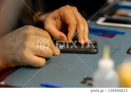 Expert Technician Repairing Phone at a Workspace With Tools and Components in a Well-Lit Environment 136890625