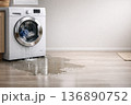 Washing Machine Leaks Water Onto Floor, Creating a Puddle in Laundry Room During Daytime 136890752