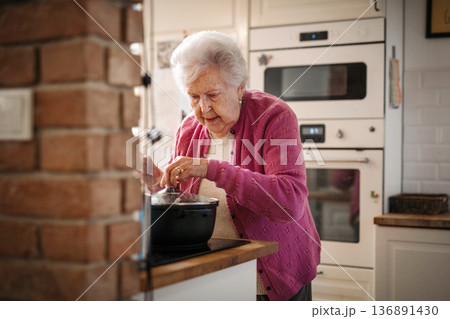 Older woman cooking lunch in kitchen. Older woman cooking lunch in kitchen. 136891430