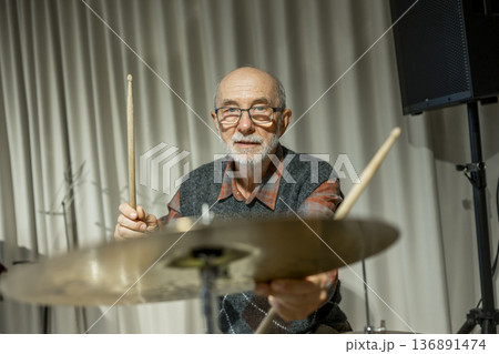 Senior man enjoying his hobby playing drums. Senior man enjoying his hobby playing drums. 136891474