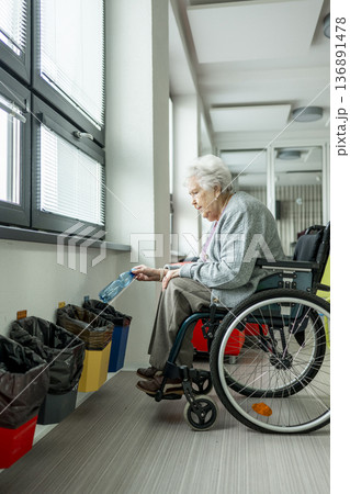 Senior woman in wheelchair sorting plastic bottle for recycling. Senior woman in wheelchair sorting plastic bottle for recycling. 136891478