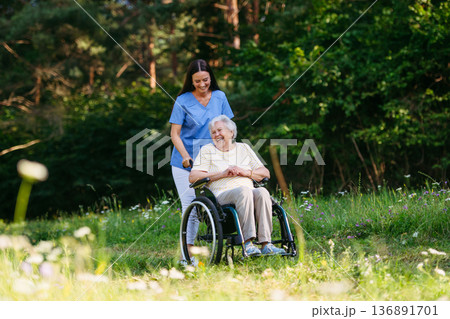 Home nurse taking care of elderly woman in wheelchair. Home nurse taking care of elderly woman in wheelchair. 136891701