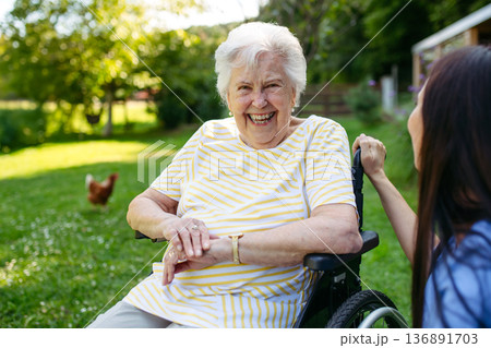 Home nurse taking care of elderly woman in wheelchair. 136891703