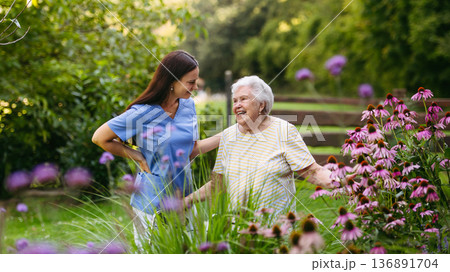 Home nurse spending time with elderly lady patient in garden. Home nurse spending time with elderly lady patient in garden. 136891704