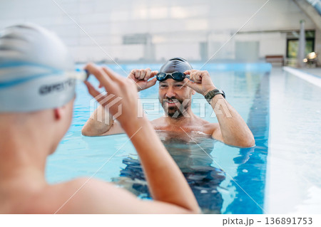 Father and teenage son enjoying swim training together. Father and teenage son enjoying swim training together. 136891753