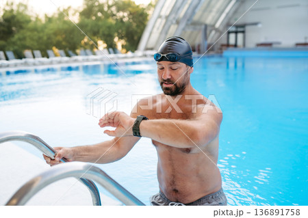 Male swimmer getting out of the pool after swim training. Male swimmer getting out of the pool after swim training. 136891758