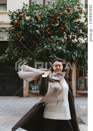 Woman Posing Confidently Against Orange Tree in Street Woman Posing Confidently Against Orange Tree in Street 136892892