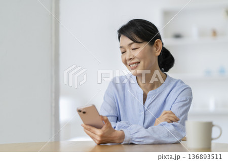 スマートフォンの画面を見る笑顔の50代後半の女性 スマートフォンの画面を見る笑顔の50代後半の女性 136893511