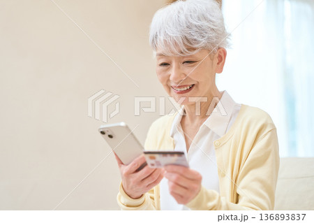 マイナンバーカードとスマホを連携するシニア女性 136893837