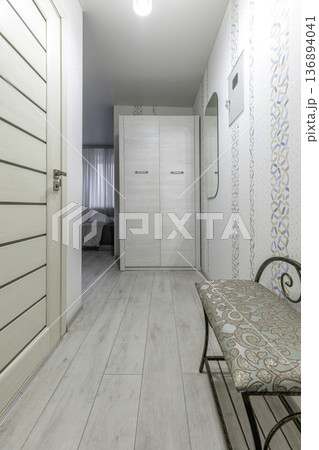 Light Hallway Interior with White Wardrobe and Patterned Bench 136894041