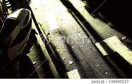 Motorcycle's Tail and Road Markings Under Dramatic Sunlight and 136895027