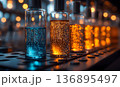 Row of illuminated laboratory bottles with blue and orange liqui 136895497