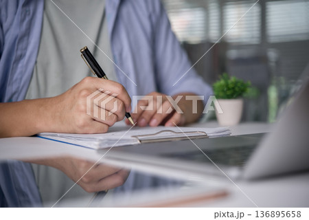 Close-up hand man writing notes on document clipboard. Student study, employee work office desk. Check report, fill application form, signing contract, paperwork, planning, list. 136895658
