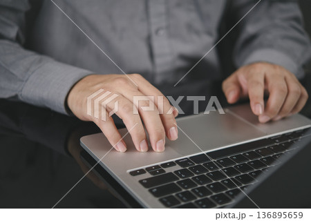 Close-up hand on laptop. Businessman working on computer, office desk. Navigating website, online browsing. Business technology concept, digital work, project management, employee using, clicking. 136895659