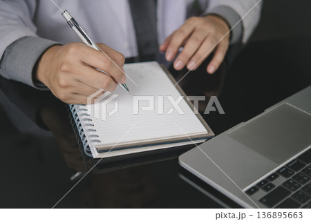 Doctor hand pen writing notes notebook. Medical healthcare concept. Physician work office desk, laptop. Write patient prescription, diagnosis, report, treatment plan. Close-up record history data. Doctor hand pen writing notes notebook. Medical healthcare concept. Physician work office desk, laptop. Write patient prescription, diagnosis, report, treatment plan. Close-up record history data. 136895663