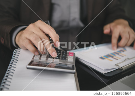 Accountant hand holding pen, use calculator, pointing financial data chart. Business finance concept. Man working office desk, analyze report, planning budget, corporate audit, check. Accountant hand holding pen, use calculator, pointing financial data chart. Business finance concept. Man working office desk, analyze report, planning budget, corporate audit, check. 136895664