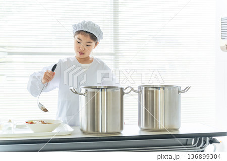 白衣を着て大鍋の料理を配膳する給食当番の女の子 白衣を着て大鍋の料理を配膳する給食当番の女の子 136899304