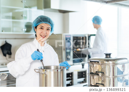 厨房で大鍋で調理する衛生白衣を着た女性調理師 給食センター 給食室 厨房で大鍋で調理する衛生白衣を着た女性調理師 給食センター 給食室 136899321