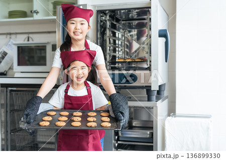 キッチンでオーブンを使ってクッキーを焼く女の子たち キッチンでオーブンを使ってクッキーを焼く女の子たち 136899330