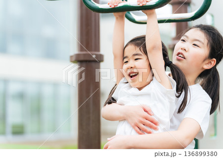 公園の雲梯で遊ぶ女の子 136899380