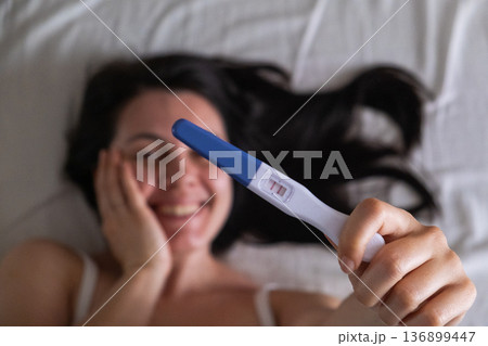 Surprised Woman with Positive Pregnancy Test 136899447