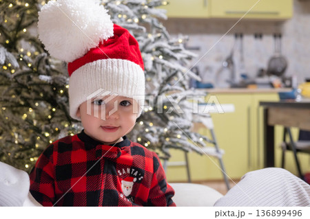 Toddler in Santa Hat by Frosted Christmas Tree with Lights Toddler in Santa Hat by Frosted Christmas Tree with Lights 136899496