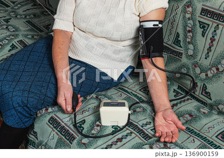 Grandma takes her blood pressure sitting on the couch Grandma takes her blood pressure sitting on the couch 136900159