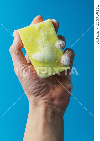 Dish detergent. Washing sponge in a person's hand 136900161