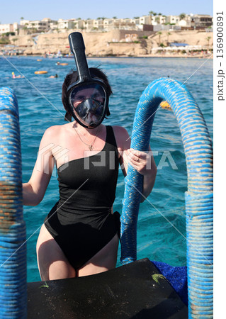 A woman overcomes her fear as she puts on a snorkel mask for the first time and dives into the water A woman overcomes her fear as she puts on a snorkel mask for the first time and dives into the water 136900891