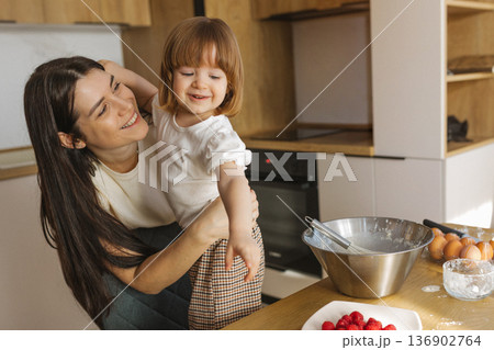 Mother and little daughter baking together in modern kitchen at home, happy family cooking and spending time together 136902764