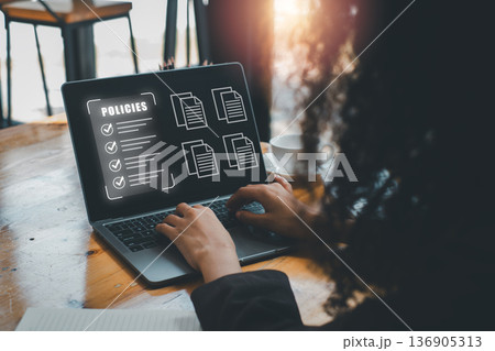 Professional woman analyzing digital documents and policies on a laptop in a contemporary office environment. Professional woman analyzing digital documents and policies on a laptop in a contemporary office environment. 136905313