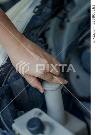 Close up of a hand of woman is checking a liquid coolant pot Close up of a hand of woman is checking a liquid coolant pot 136906163