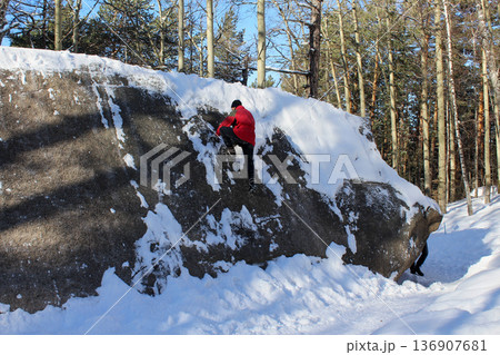 Man rock climbing on snowy mountain cliff. Winter sport outdoor lifestyle. Krasnoyarsk Stolby national park adventure 136907681