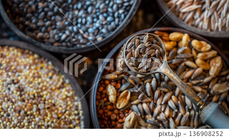 Array of bowls filled with various types of whole grains, with a focus on a spoonful of seeds. 136908252