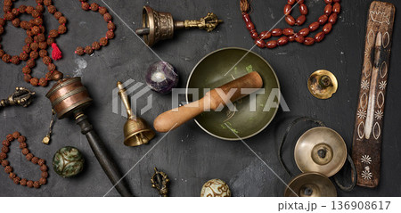 Tibetan singing bowl, wooden resonator, ritual vajras, bell, prayer wheel, rosary beads, and incense on a black background Tibetan singing bowl, wooden resonator, ritual vajras, bell, prayer wheel, rosary beads, and incense on a black background 136908617