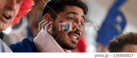 Excited football fans supproting French national team in live soccer match at stadium. 136908927