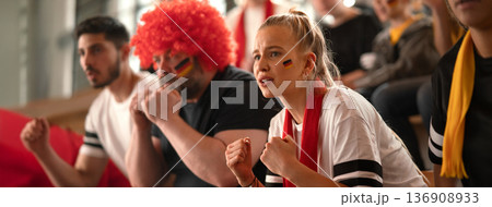 Worried football fans supproting German national team in live soccer match at stadium. 136908933