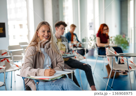 Group of college students attending lecture in university hall. Group of college students attending lecture in university hall. 136908975