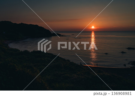 夕陽に染まる海辺と佇む人々のシルエット 136908981