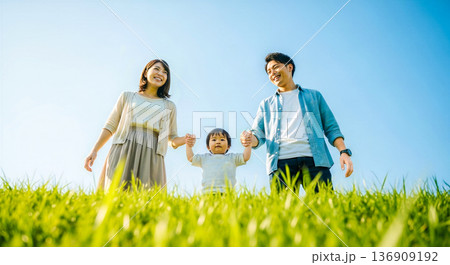 青空と芝生の広場で手を繋ぐ3人家族の笑顔 親子 幸せ 子育て ライフスタイル 背景素材 広告 青空と芝生の広場で手を繋ぐ3人家族の笑顔 親子 幸せ 子育て ライフスタイル 背景素材 広告 136909192
