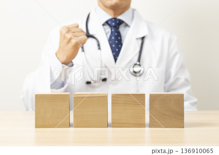 ガッツポーズをする医者と無地のブロック 136910065