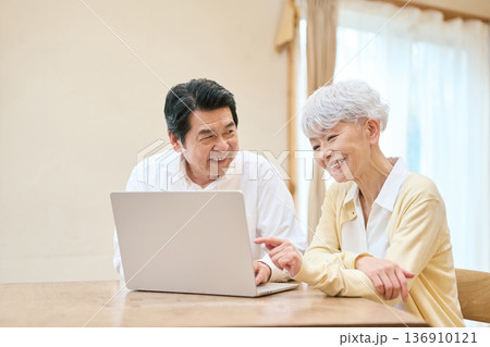 リビングでPCを使うアジア人シニア夫婦 136910121