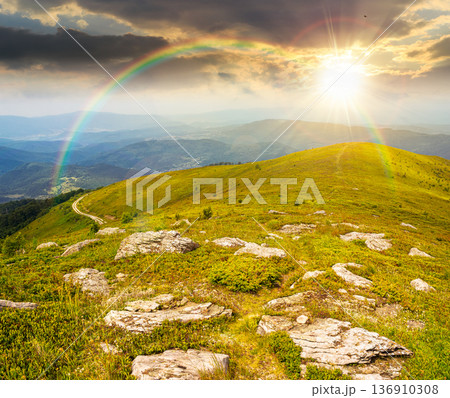 mountain landscape in summer with rocks at sunset. green grass under blue sky in dramatic evening light. alpine meadow and rolling hills with boulders. timeless nostalgia book cover with rainbow mountain landscape in summer with rocks at sunset. green grass under blue sky in dramatic evening light. alpine meadow and rolling hills with boulders. timeless nostalgia book cover with rainbow 136910308