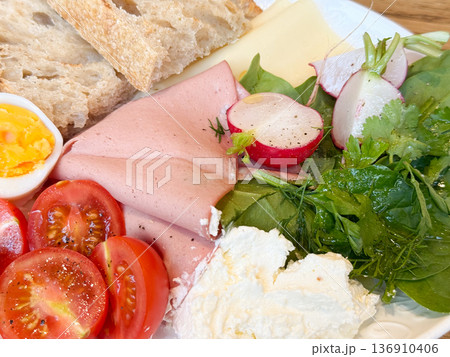 Closeup breakfast ham cheese and radish beside eggs and bread. Balanced brunch plate, protein source, natural ingredients, and wholesome nutrition concept. Closeup breakfast ham cheese and radish beside eggs and bread. Balanced brunch plate, protein source, natural ingredients, and wholesome nutrition concept. 136910406
