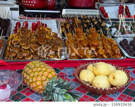 Assorted caramelized fruits and pears with pineapple on market table. Seasonal abundance, street gastronomy, harvest celebration, and traditional dessert concept. Assorted caramelized fruits and pears with pineapple on market table. Seasonal abundance, street gastronomy, harvest celebration, and traditional dessert concept. 136910416