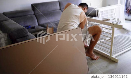 Expectant father preparing a nursery by assembling a wooden crib Expectant father preparing a nursery by assembling a wooden crib 136911141
